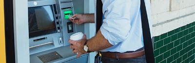 man at ATM with coffee